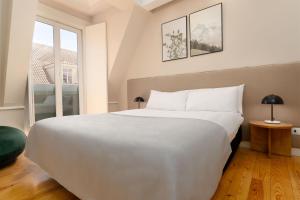 a bedroom with a large white bed and a window at Limehome Lisbon Rua do Arsenal in Lisbon