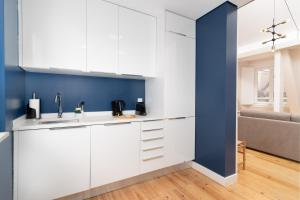 a kitchen with white cabinets and a blue wall at Limehome Lisbon Rua do Arsenal in Lisbon