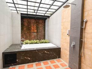 La salle de bains est pourvue d'une baignoire avec des plantes. dans l'établissement Baleeyan Residence, à Thalang