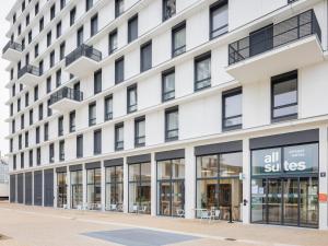 ein großes weißes Gebäude mit Glasfenstern in der Unterkunft All Suites Appart Hotel Le Havre in Le Havre