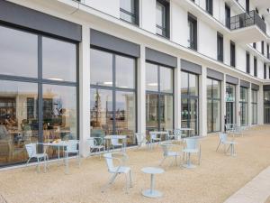 a group of tables and chairs in front of a building at All Suites Appart Hôtel - Le Havre Centre - Les docks in Le Havre
