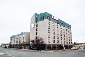 een hoog wit gebouw op een straat met een straat bij Nomad Hotel & Suites in Fort McMurray