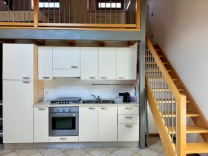 a kitchen with white cabinets and a staircase at 1Dest - Segantini Loft in Arco