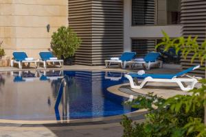 فندق عمان كورب في عمّان: مسبح وكراسي الصالة زرقاء وبيضاء بجانب مبنى