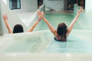 Duas raparigas estão num escorrega aquático. em Ferienwelt Kesselgrub Hotel in Altenmarkt-Zauchensee em Altenmarkt im Pongau