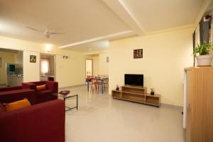 a living room with a couch and a television at Guesture Stays - Dwellington, Electronics City Phase 2 in Bangalore