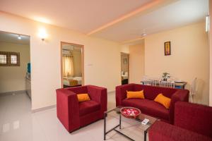 a living room with two red couches and a table at Guesture Stays - Dwellington, Electronics City Phase 2 in Bangalore