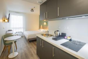 a kitchen with a sink and a room with a bed at All Suites Appart Hôtel - Le Havre Centre - Les docks in Le Havre