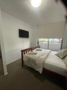 a bedroom with a bed and a flat screen tv at Ocean view 2 Bedroom apartment in Sydney