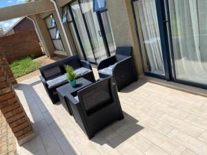 a patio with three chairs and a table with a potted plant at Remarkable 2-Bed Apartment in Harare in Harare