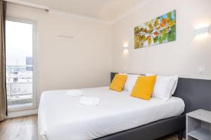 a bedroom with a bed with yellow pillows and a window at Star Of Life in Courbevoie