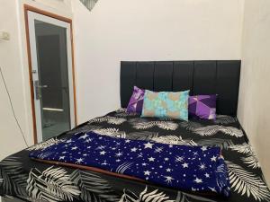 Una cama con cabecero negro y almohadas. en OYO 93841 Panorama Dewi, en Subang