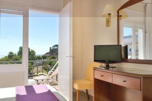 a bedroom with a desk with a television and a balcony at RVHotels Avenida in Tossa de Mar
