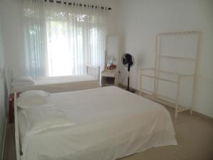 a white bedroom with two beds and a window at Ananthaya -the infinity in Kalutara