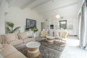 ein Wohnzimmer mit einem Sofa und Stühlen sowie eine Küche in der Unterkunft Hotel le Mandala in Saint-Tropez