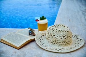 a straw hat and a book and a drink on a table at Soho Hutor in Bosteri