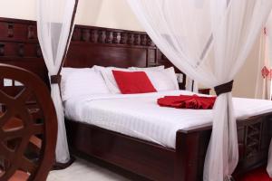 - une chambre avec un lit doté d'oreillers et de rideaux rouges dans l'établissement White Peacock Resort, à Tezo