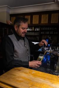 un hombre sentado en un bar con una bebida en Kirchenwirt Schladming, en Schladming