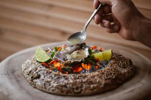 a person holding a spoon over a food dish at Lago Resort Menorca - Suites del Lago Adults Only in Cala en Bosc