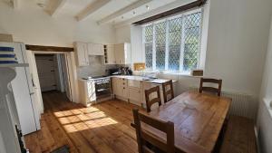 cocina con mesa de madera y ventana grande en Place Lodge, en Porthscatho