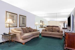a living room with two couches and a television at Ramada by Wyndham Henderson/Evansville in Henderson