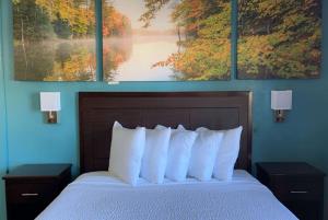 a bedroom with a bed with three paintings on the wall at Days Inn & Suites by Wyndham Springfield on I-44 in Springfield