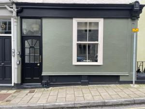 a green house with a black door and windows at Ferrymans Rest in Dartmouth