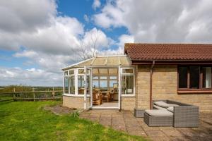 a house with a conservatory with a table and chairs at Tanglewood in West Ashton