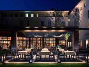 an outdoor patio with tables and chairs at night at Mercure Salzburg City in Salzburg