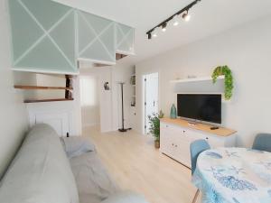 a white living room with a tv and a bed at Morriña Atlantica Duplex Playa America in Nigrán