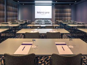 uma sala de conferências com mesas e cadeiras e um ecrã em Mercure Salzburg City em Salzburgo