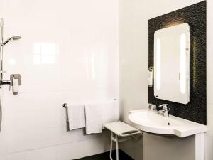 a white bathroom with a sink and a mirror at ibis Orange Centre in Orange