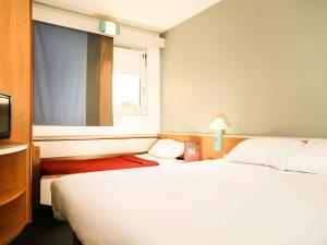 een slaapkamer met een groot wit bed en een raam bij ibis Orange Centre in Orange