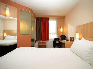 um quarto de hotel com uma cama branca e uma secretária em ibis Montpellier Centre Polygone em Montpellier