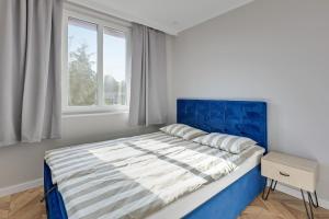 a bedroom with a bed with a blue headboard and a window at Dom & House - Apartament Kościuszki Family in Sopot