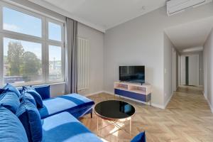a living room with a blue couch and a tv at Dom & House - Apartament Kościuszki Family in Sopot