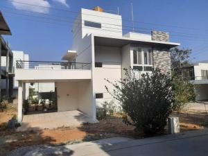a white house with a balcony on a street at The RusticVibe-Villa with Garden 30 km frm Ecity in Bangalore