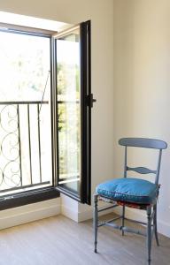 una silla azul sentada frente a una ventana en Gîte de l'Escanson un temps pour soi en Robion en Luberon