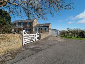 una casa con una puerta blanca y una valla en Pomme Blushe House, en Shipton Gorge