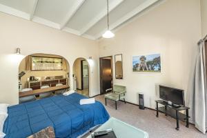 um quarto com uma cama azul e uma televisão em Riverside Motel em Whanganui