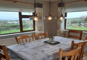 a dining room with a table and two windows at Mourneen Cottage, Cleggan in Cleggan