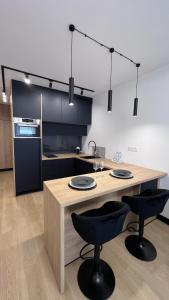a kitchen with a wooden table and two black chairs at Apartament Poleska in Częstochowa