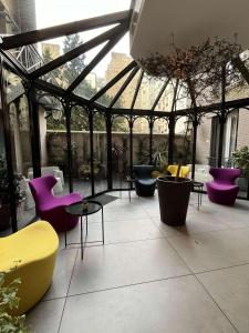 un giardino d'inverno con tavoli e sedie viola e gialle di Mercure Paris Alesia a Parigi