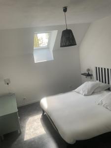 um quarto branco com uma cama e uma janela em Charmant gîte avec extérieur et piscine partagée em Mespaul