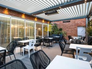 an outdoor patio with tables and chairs and a brick wall at ibis Styles Deauville Centre in Deauville