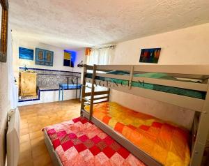 Maison de village typique bord de mer في ألغاجولا: غرفة نوم مع سريرين بطابقين مع بطانية ملونة