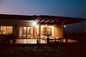 a house with a lit up patio at night at Family Friendly Farmhouse Retreat: 3BR, Lawns, BBQ, errace, Chopal, Historic Water Well. Ideal for Work and Outdoor Activities. Close to Groceries, Cafés, Fully Secured Gated Community, CCTV in Islamabad