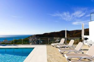 a pool with chairs and the ocean in the background at Casa Grace in Nerja