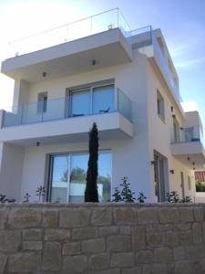 una casa bianca con un albero di fronte di Katikies Superior Villa a Pissouri