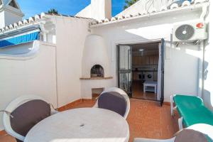 eine Terrasse mit einem Tisch und Stühlen sowie eine Küche in der Unterkunft 19C Las Palmas Oasis de Capistrano in Nerja